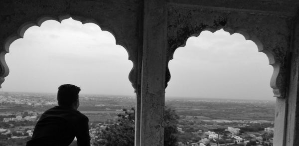 Rear view of man looking at sea against sky