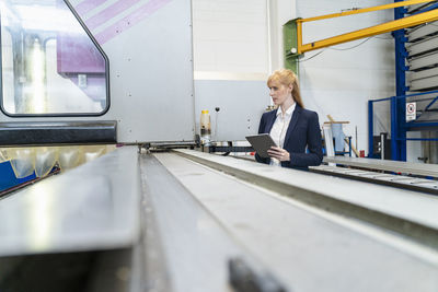 Businesswoman with tablet at conveyor belt in factory