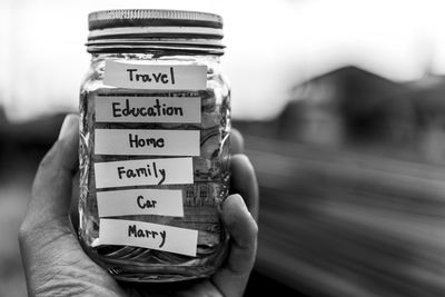 Close-up of hand holding jar with text outdoors