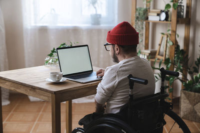 Man in wheelchair using laptop at home