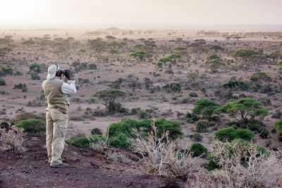 Rear view of woman photographing in desert