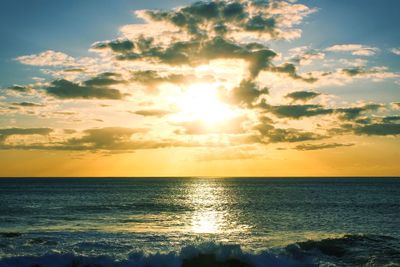 Scenic view of sea against cloudy sky during sunset