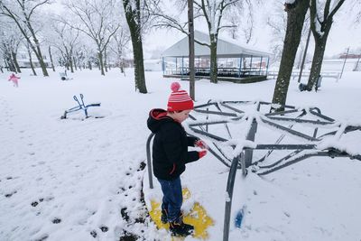 Boy standing on snow covered playground