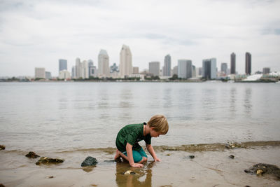 Full length of boy on water against cityscape