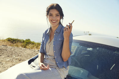 Smiling young woman holding car keys at a car