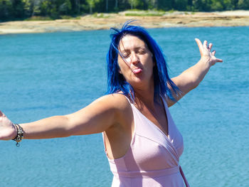 Young woman standing against blue sea