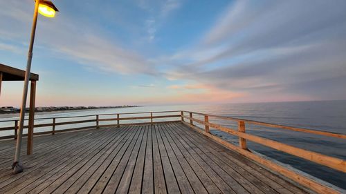 Pier over sea against sky during sunset