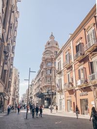 People walking on road amidst buildings against clear sky