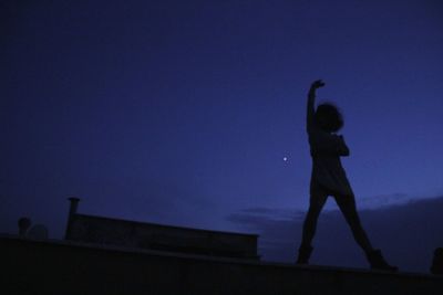 Low angle view of silhouette man against clear blue sky