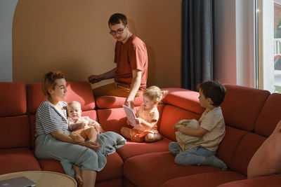 Big family on couch at home. parents with kids on sofa during sunny day spending free time. mother