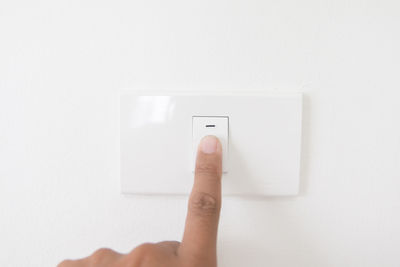 Close-up of hand holding camera against white background