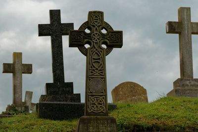 Low angle view of cross in cemetery against sky