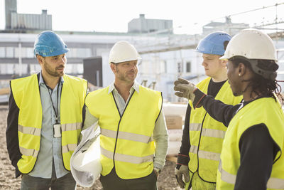 Construction worker discussing with architects at site