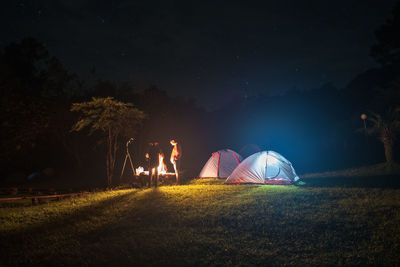 Illuminated tent on field against sky at night