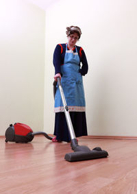 Full length of woman cleaning house with vacuum cleaner