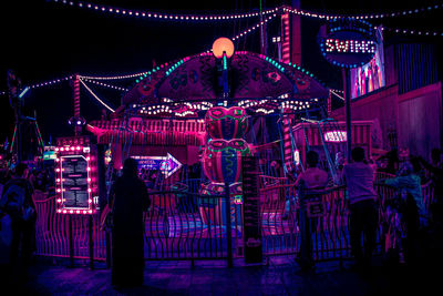 People in illuminated amusement park at night