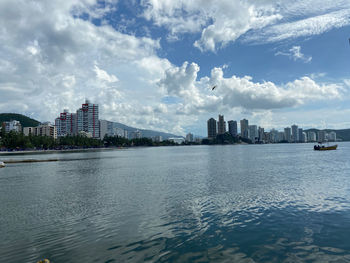 Sea by buildings against sky in city