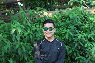 Portrait of smiling young man standing by plants