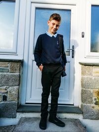 Portrait of teenage girl standing at entrance of building