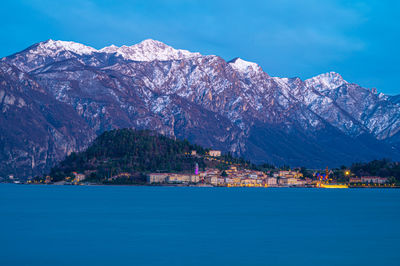 The town of bellagio, in winter, at dusk, from tremezzina, with the snow-capped mountains.