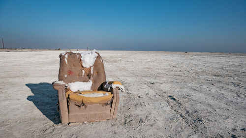 Couch on a salt flat against clear sky