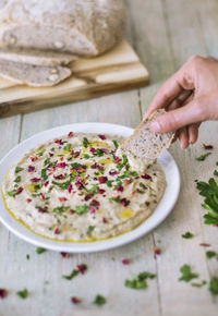 Person holding bread and dipping in hummus