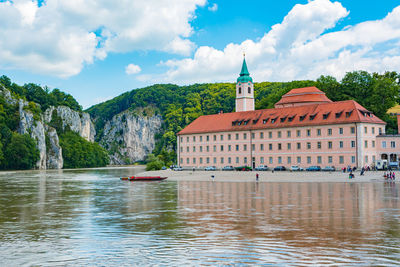 View of building by lake against cloudy sky