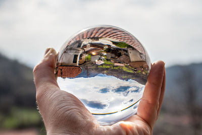 Close-up of person holding crystal glass against sky