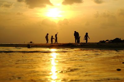 Silhouette of people on beach at sunset