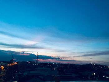 Illuminated city against sky at sunset