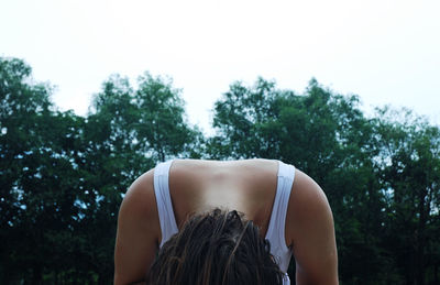 Close-up of woman bending against trees