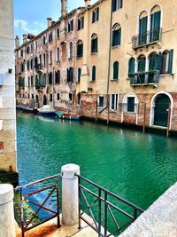 Canal by buildings in city against sky