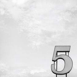 Low angle view of number against cloudy sky