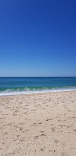 Scenic view of beach against clear blue sky