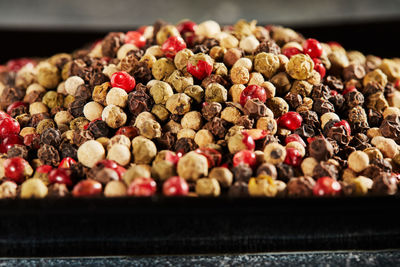 Multi-colored peppercorns on black plate with reflection