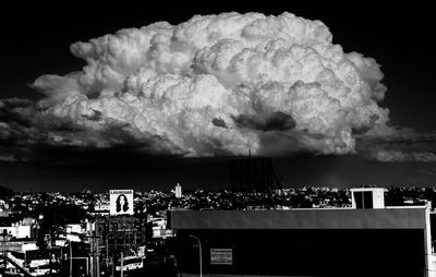 Illuminated cityscape against cloudy sky