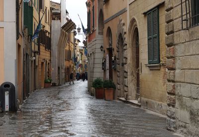 Wet street amidst buildings in city