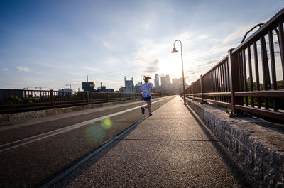 Rear view of woman running on road against sky