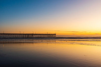 Pier over sea against sky during sunset