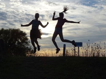 Full length of men jumping on field against sky