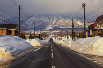 Road amidst snowcapped mountains against sky during winter