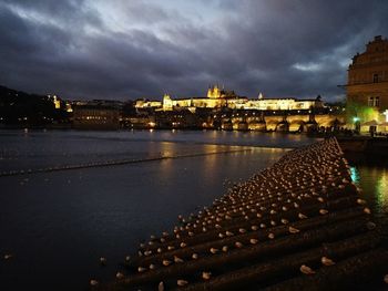 Illuminated buildings by river at night