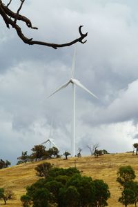 Low angle view of wind turbines on field against sky