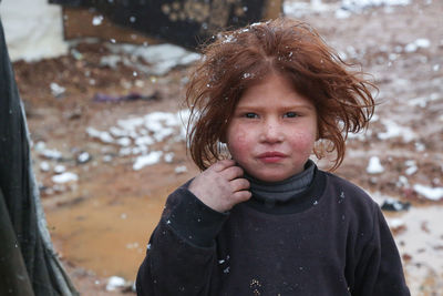 A beautiful refugee girl during a snowfall on a syrian refugee camp near the turkish border