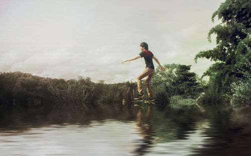 Side view of man in lake against sky