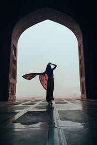 Full length of woman standing on umbrella against sky