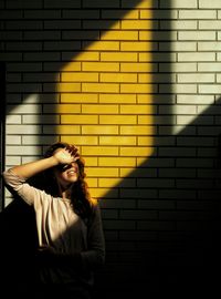 Beautiful young woman against wall during sunny day