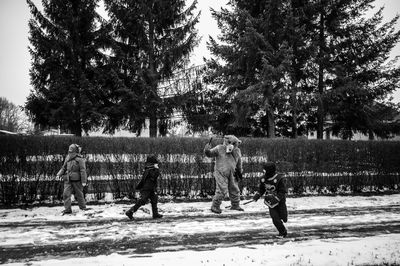 Children playing on field against trees during winter