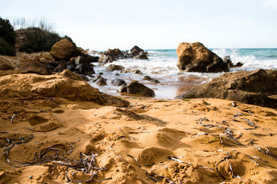 Rock formation on beach against sky