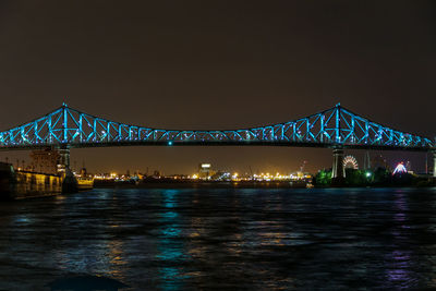 Illuminated bridge over water at night